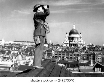 Aircraft spotter searches the sky with binoculars during the Battle of Britain. St. Paul's Cathedral is in the background. World War 2, ca. 1940-41.