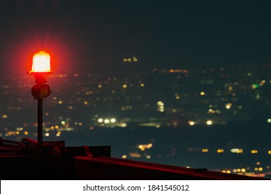 aircraft warning light on top of a highrise of building at night and cityscape as background