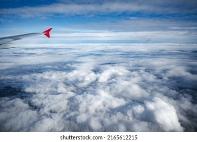 Aircraft wing above beautiful clouds and blue sky, close up