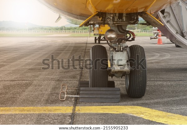 The aircraft\'s wheels are blocked by chock\
block. Rubber wheel chock under\
wheel.