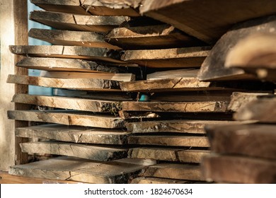 Air-drying sawn wooden plank slab pile under canopy at home backyard prepared for carpentry diy hobby. Woodshed store at house yard. Timber material stacked for woodworking .