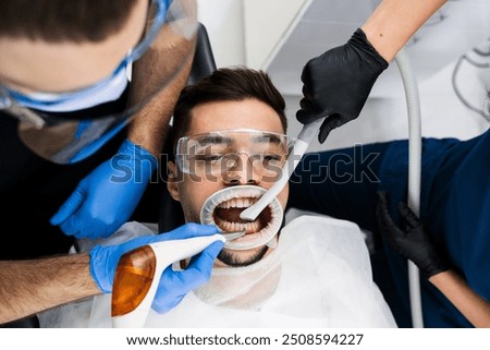 Airflow teeth cleaning process. Dentist removes plaque from teeth with airflow equipment. Dental hygiene procedure