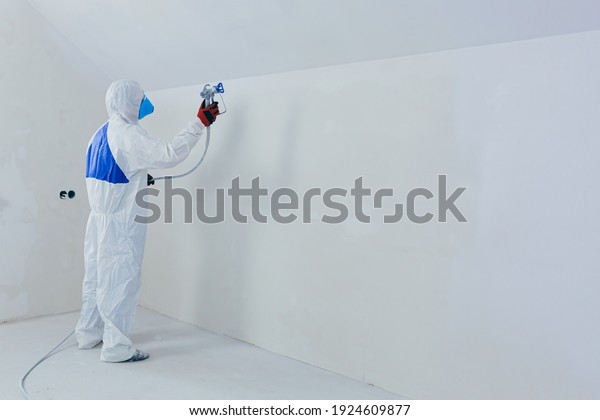 Airless spray paint. The worker\
paints the wall with an airless spray in white, an experienced\
worker sprays the paint on the surface with a mechanical air\
tool