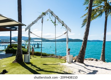 Airlie Beach, Queensland, Australia - December 2021: Children Playing Around A Rope Swing On The Beachfront Of A Luxury Resort Hotel On A Hot Summer Day