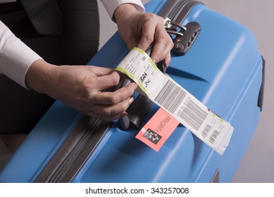 Airline Check In Luggage Tag Being Attached To A Suitcase. Priority Tags