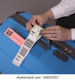 Airline Check In Luggage Tag Being Attached To A Suitcase. Priority Tags