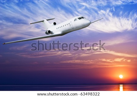 Airliner flying above tropical sea at sunset