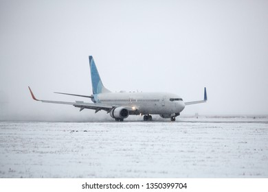 Airliner On Runway In Blizzard. Aircraft During Taxiing On Landing Strip During Heavy Snow. Passenger Plane In Snow At Airport.