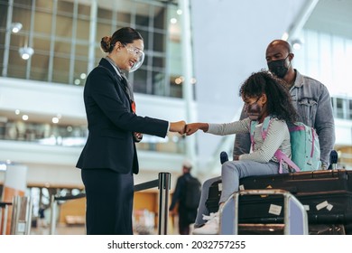 Airlines Attendant And Young Girl Of Traveler Family Giving Fist Bumps To Each Other At Boarding Gate. Ground Staff At Airport Terminal Greeting Girl In Face Mask With Her Father During Pandemic.