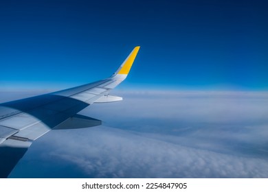 An airlines plane in the sky. Image of an airplane wing at sunset with the sky in the background. Air travel and vacation trips. Airfare and flight reservation.
