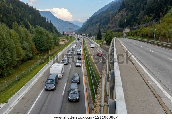 Airolo,\
Switzerland - 30 September 2018: vehicles waiting in line for\
entering Gotthard tunnel on the Swiss\
alps