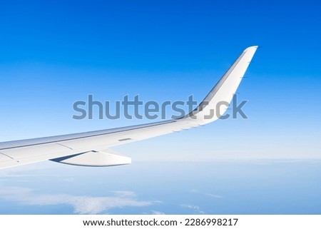 Airplain wing view thrue window in the sky. Clouds and sky as seen through porthole of an aircraft with airplane's wing