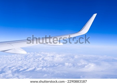 Airplain wing view thrue window in the sky. Clouds and sky as seen through porthole of an aircraft with airplane's wing