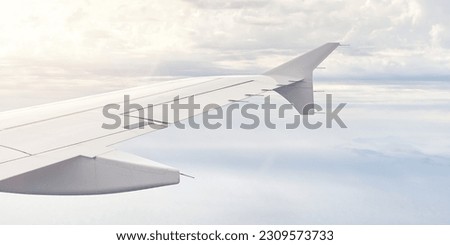 Airplain wing view thrue window in the sky. Clouds and sky as seen through porthole of an aircraft with airplane's wing