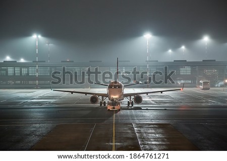 Airplane at the aiport pushed back at night, rainy evening