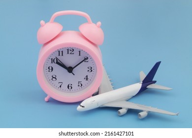 Airplane With Alarm Clock On Blue Background. Time For Travel And Flight Time Concept. 