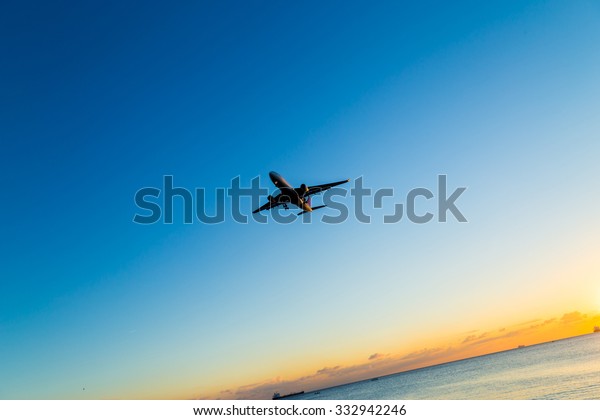 An airplane approaching the runway for landing\
during the sunset