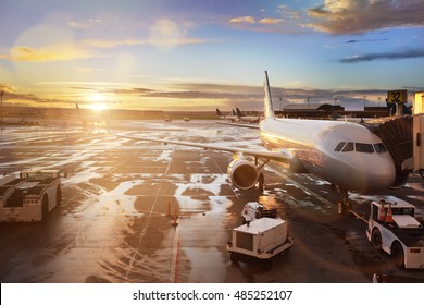 Airplane being preparing for takeoff at terminal gate in international airport at sunrise