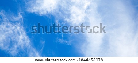 Airplane in the blue sky with clouds from below, high flying passenger plane with condensation trail. jet plane flying overhead diagonally in sky with sunlight. Bottom view