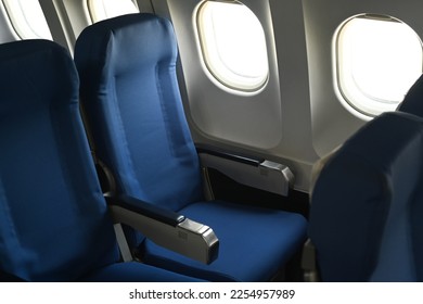 Airplane cabin interior, empty comfortable seats in economy class with portholes
