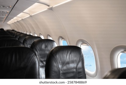 Airplane cabin interior,Empty comfortable row seats in economy class with portholes,Aerial view through airplane window,Inside Passenger plane looking out at cloud sky,Concept for transport Travel