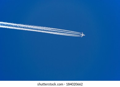 airplane with condensation trails at blue sky