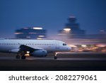 Airplane during take off on airport runway at night against air traffic control tower. Plane in blurred motion at night.
