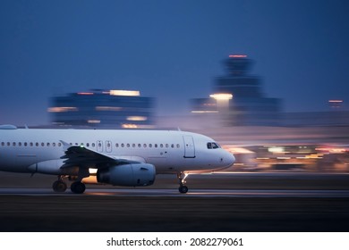 Airplane during take off on airport runway at night against air traffic control tower. Plane in blurred motion at night. - Shutterstock ID 2082279061