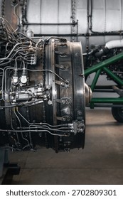 Airplane engine maintenance. Side view of old jet engine without cowling on a stand, another bigger engine in the background.