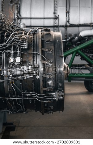 Airplane engine maintenance. Side view of old jet engine without cowling on a stand, another bigger engine in the background.