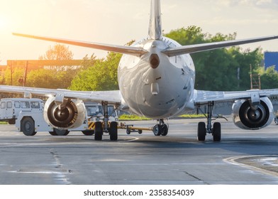 Airplane execute push back operation at airport. Aircraft service for flights before departure in the evening at sunrise. - Powered by Shutterstock