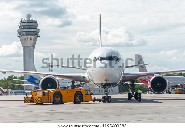 Airplane execute push back operation at airport, on\
the background ATC\
tower