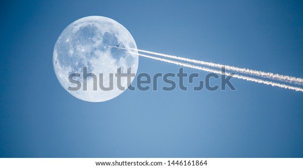 An airplane flies past the moon in the sky.\
Concept travel by plane.