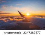 Airplane flight in sunset sky over ocean water and wing of plane. View from the window of the Aircraft. Traveling in air.