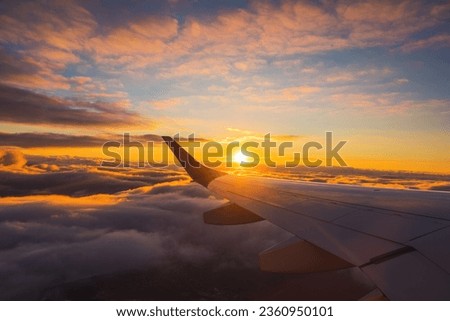Airplane flight in sunset sky over ocean water and wing of plane. View from the window of the Aircraft. Traveling in air.