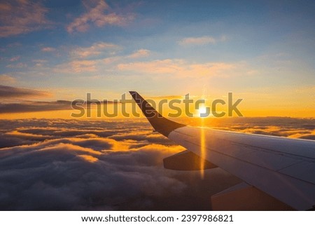 Airplane flight in sunset sky over ocean water and wing of plane. View from the window of the Aircraft. Traveling in air.