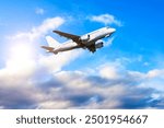 Airplane in the flight, travel background with airplane flying in the blue sky over the clouds. Flying airplane with blank livery