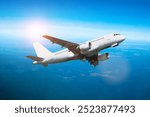 Airplane in the flight, travel background with airplane flying in the blue sky high above the ground. Flying airplane with blank livery