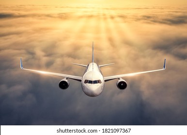 Airplane Is Flying Above The Clouds At Sunset In Summer. Landscape With Passenger  Airplane, Low Clouds, Orange Sky. Front View Of Aircraft. Business Travel. Commercial Plane. Aerial View. Take Off