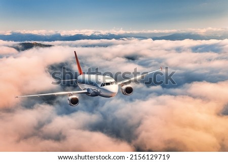 Airplane is flying above the clouds at sunset in summer. Landscape with passenger airplane, beautiful clouds,  blue sky. Aircraft is taking off. Business travel. Commercial plane. Aerial view 