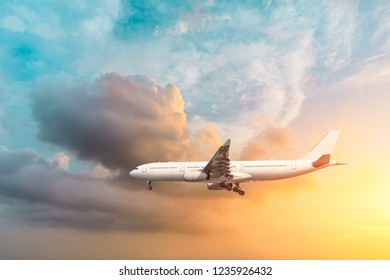 Airplane flying above dramatic clouds during sunset