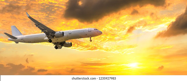 Airplane flying above dramatic clouds during sunset