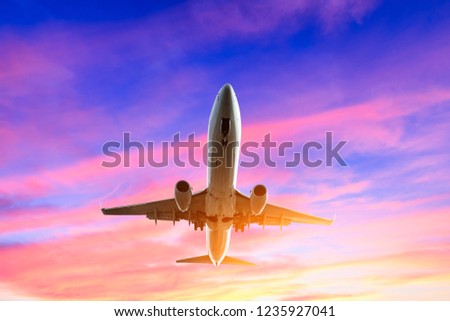 Airplane flying above dramatic clouds during sunset