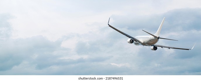 Airplane Flying In The Beautiful Sky Through The Clouds At Sunset