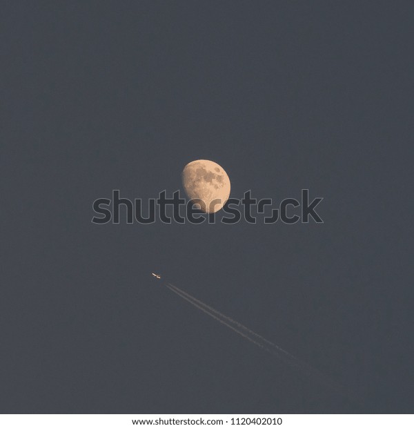 Airplane flying before the\
Moon\
