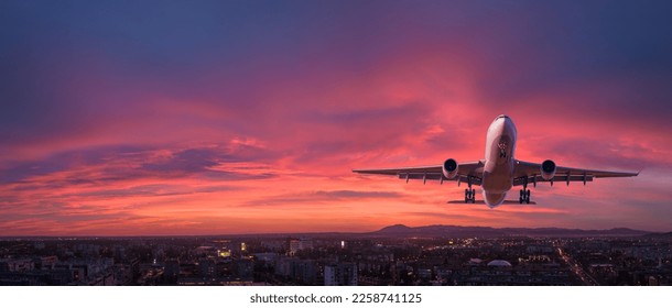 Airplane is flying in colorful sky over the city at night. Landscape with passenger airplane, skyline, purple sky with red and pink clouds. Aircraft is landing at sunset. Aerial view. Transport - Powered by Shutterstock