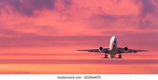 Airplane Is Flying In Colorful Sky At Sunset. Landscape With White Passenger Airplane, Purple Sky With Pink Clouds. Aircraft Takes Off. Business Trip. Commercial Plane. Travel. Aerial View. Concept