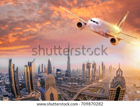Airplane is flying over Dubai against colorful sunset in United Arab Emirates