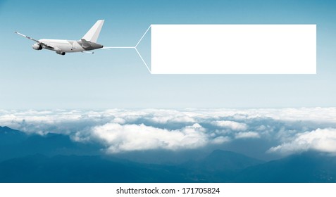 An airplane flying through the sky pulling a blank white banner to add your own message.