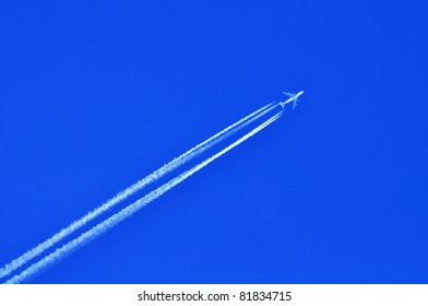 Airplane with four condensation trail on blue sky